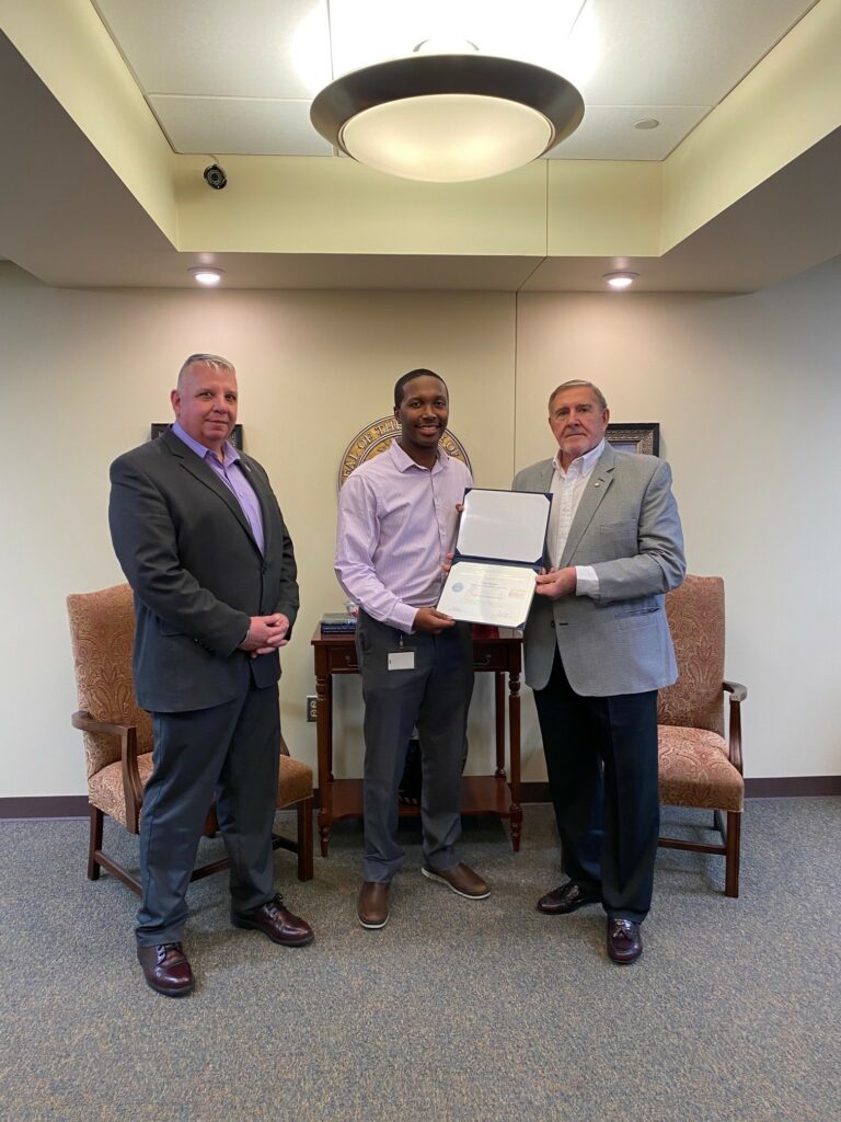 A male DWS employee Carl Danley is presented with an Employer Support of the Guard and Reserve Patriotic Employer certificate by Tom Anderson who is standing next to him