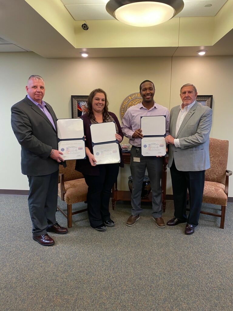 a male DWS employee and female DWS employee stand next to two men who presented them with Employer Support of the Guard and Reserve Patriotic Employer certificates